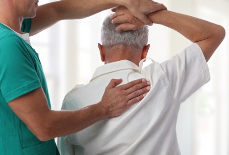 A Chiropractor Westmont IL helping adjust the shoulder of an elderly man