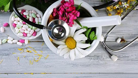 Flowers and medicine in a mortar and pestle representing Alternative Medicine Downers Grove IL